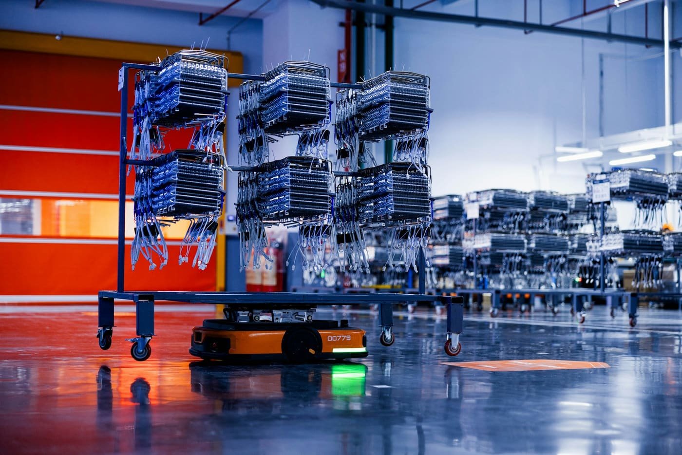 Automated guided vehicle carrying racks of metal parts across a factory floor