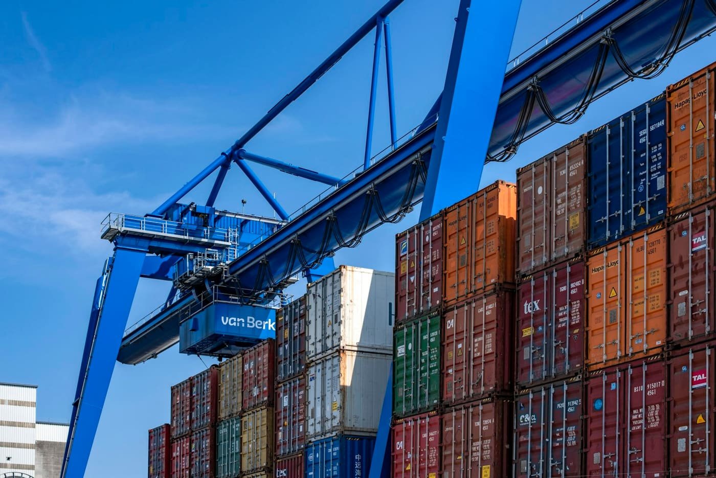 Blue gantry crane above stacked shipping containers at a terminal