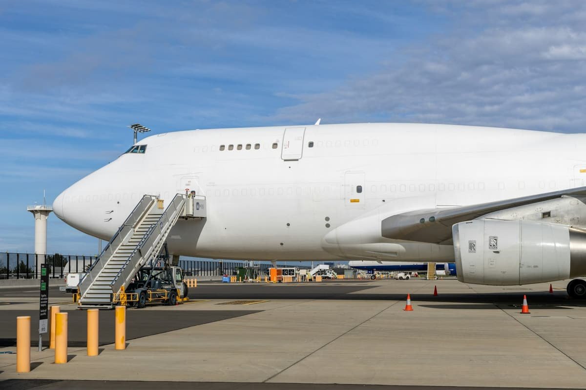 White cargo aircraft parked on an airport apron with boarding stairs attached