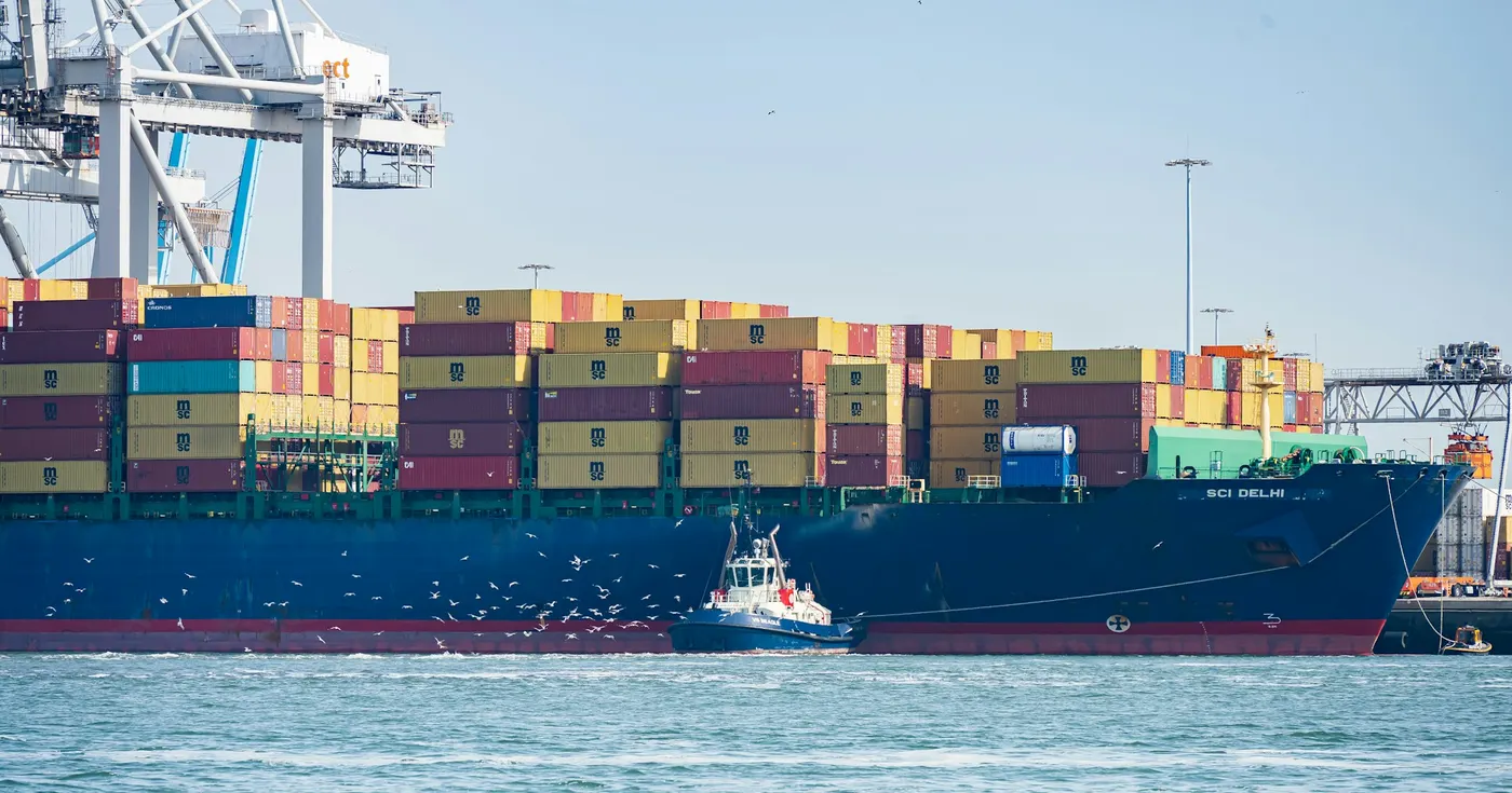Container ship at a quay with a tugboat and a quay crane during sea freight operations
