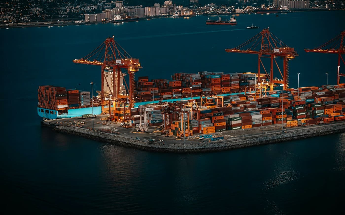 Container terminal with quay cranes and stacked containers at dusk