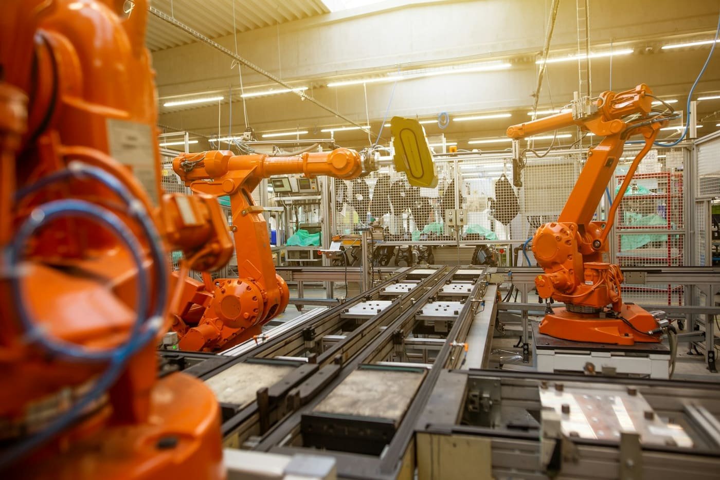 Orange robot arms working along a factory production line