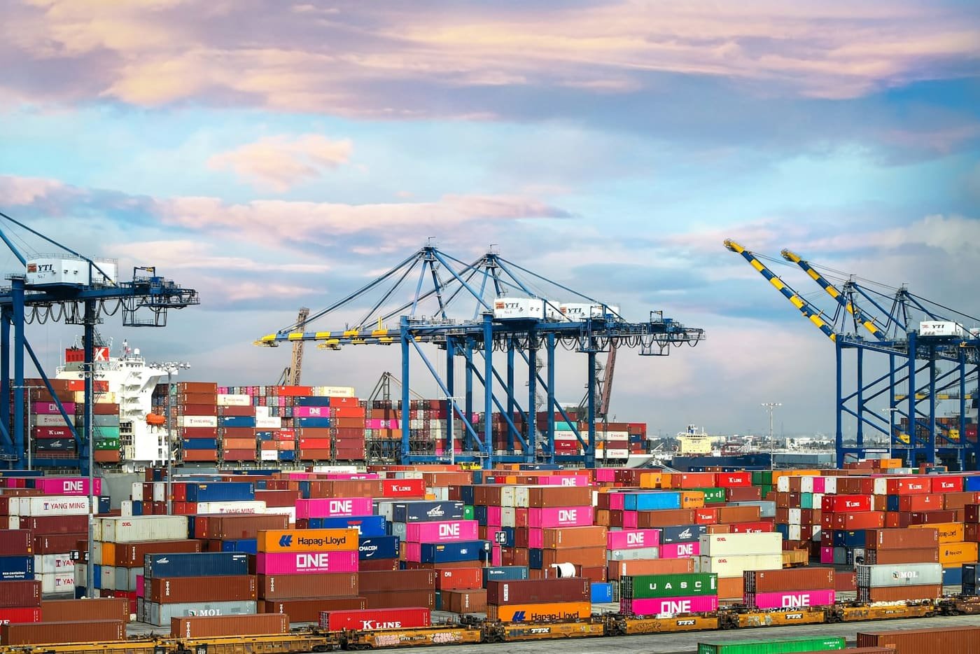 Port cranes above rows of red and blue containers