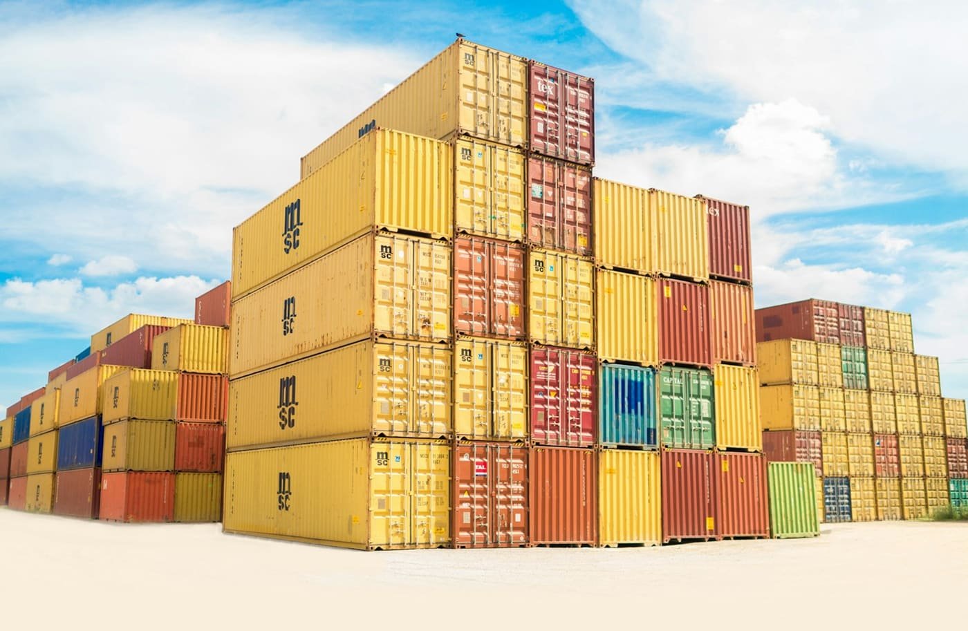 Stacks of yellow, red and green shipping containers on a yard