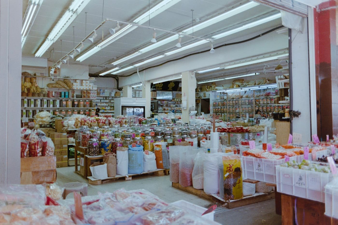 Wide aisles of a grocery and wholesale store stocked with bags, jars and boxes of goods