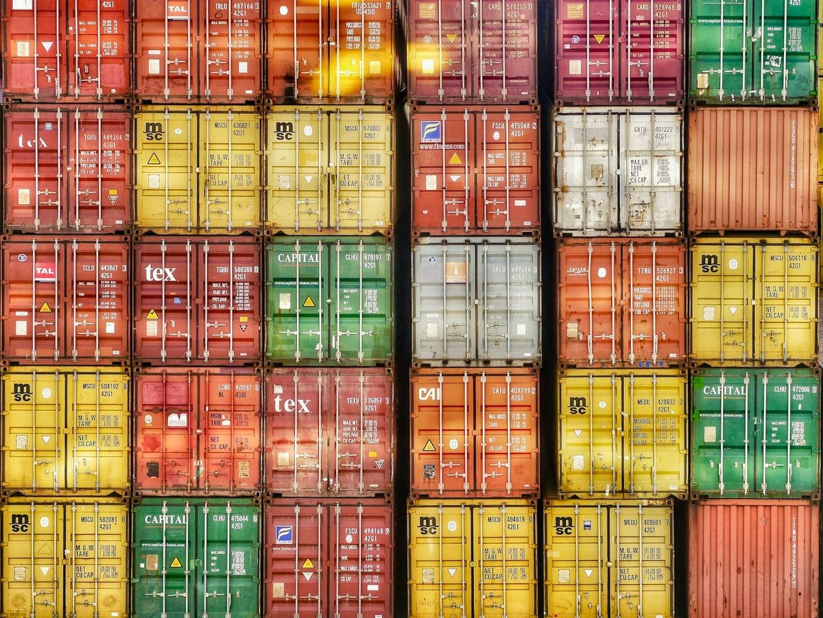 Wall of stacked colourful shipping containers whose doors show weight markings